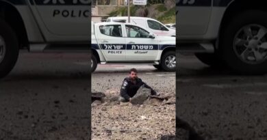 Israeli police inspect damage on the road after missile impact